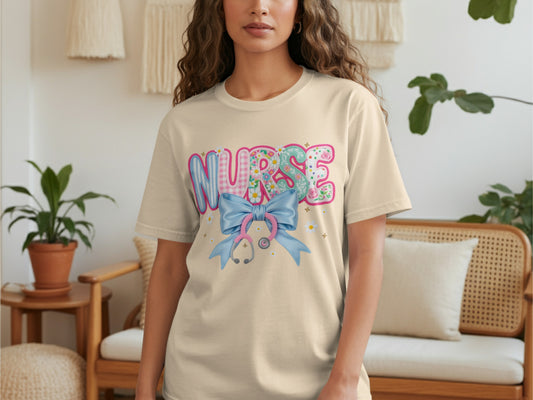 Cream t-shirt with "NURSE" text, a pink bow, and a stethoscope.