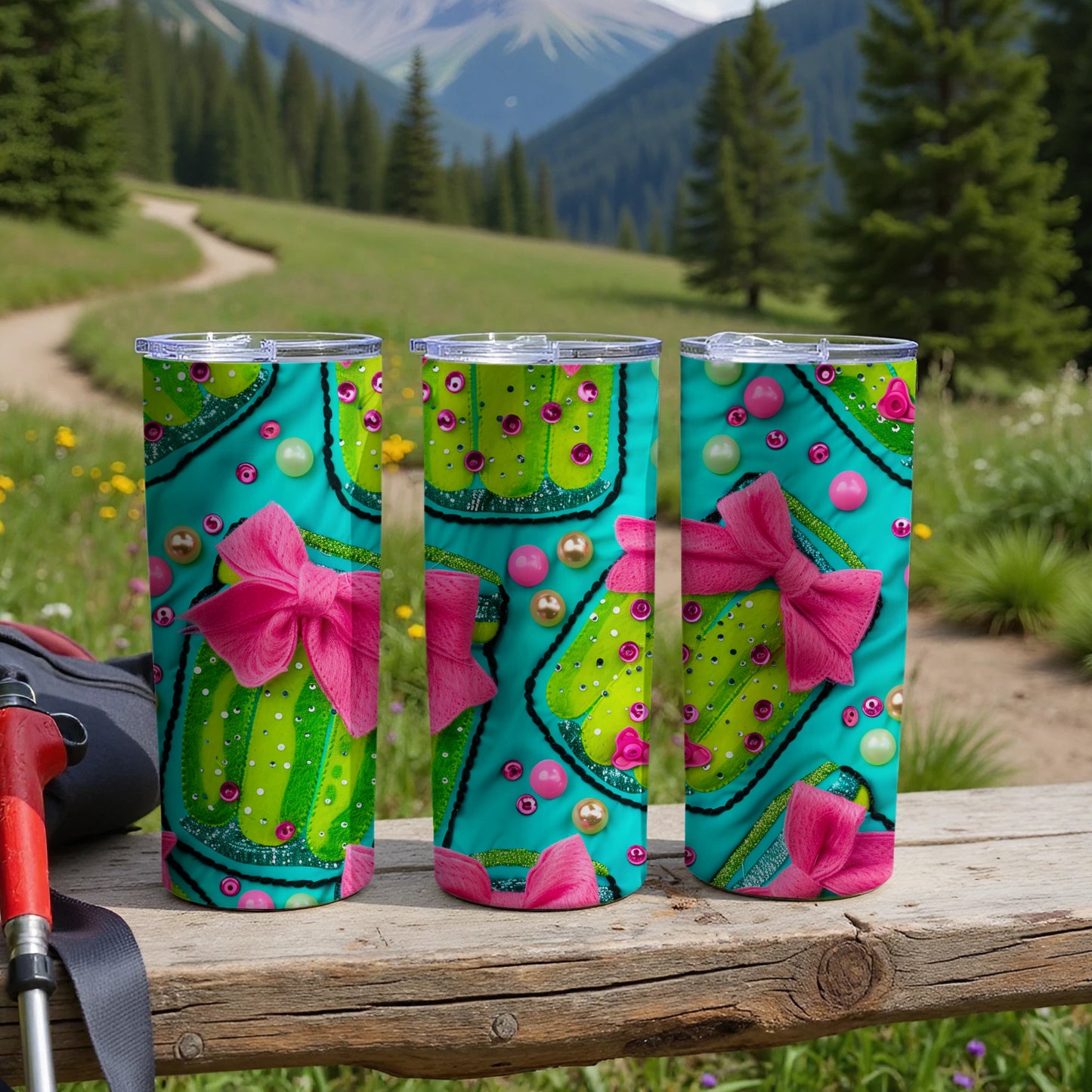 Three teal tumblers with pink bows and colorful polka dots on a wooden surface.