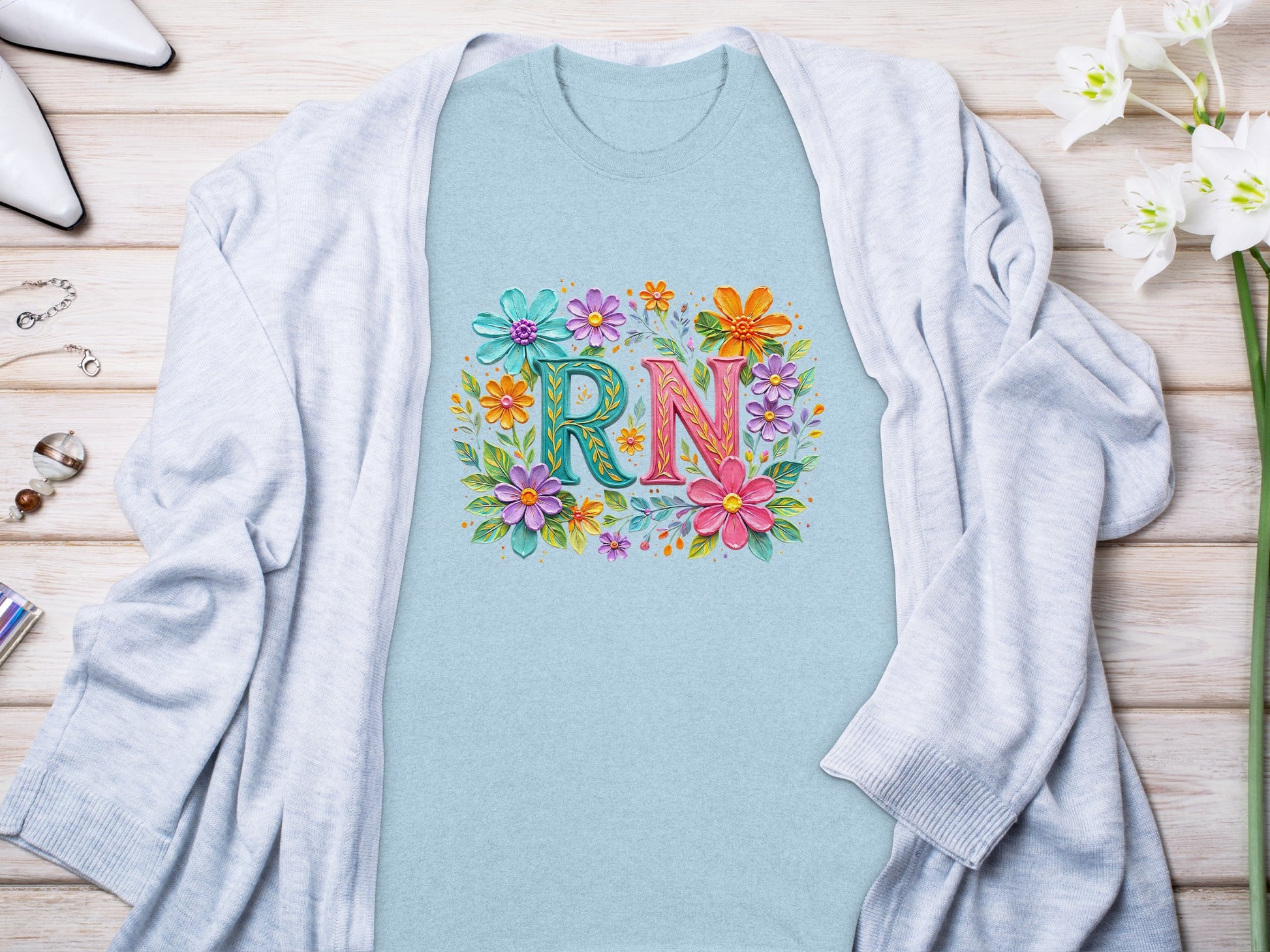 Blue t-shirt with floral letters spelling "RN" and a light grey cardigan.