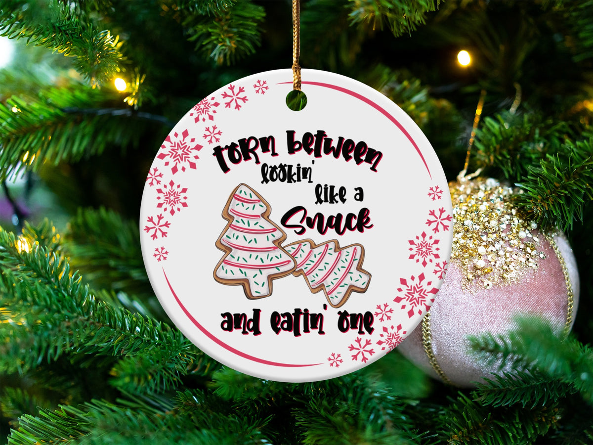 Round ornament with text "Torn between lookin' like a snack and eatin' one" and gingerbread trees.