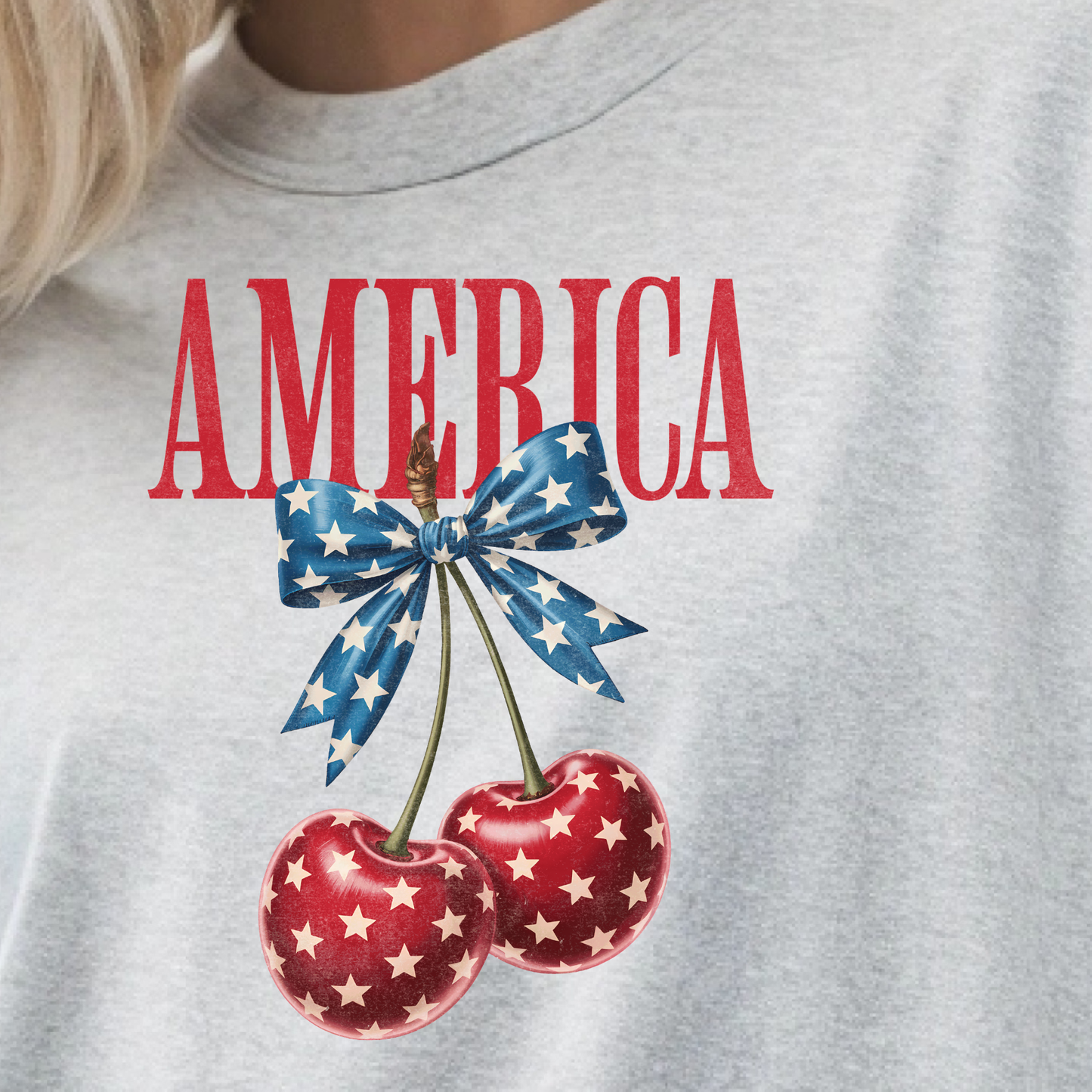 Gray t-shirt with 'AMERICA' text and cherry design featuring a blue bow.