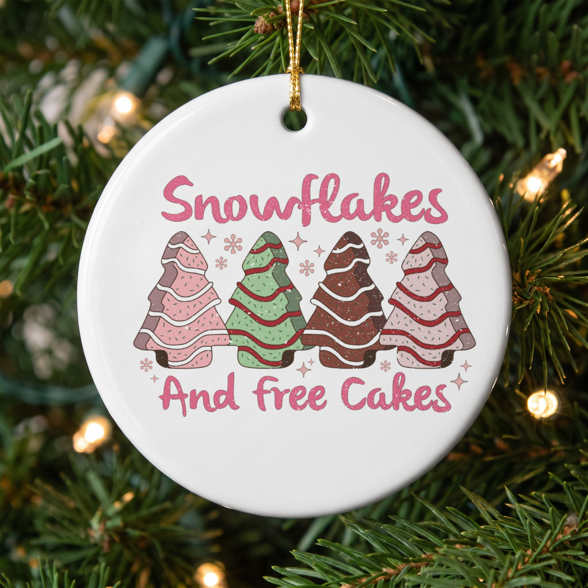 Round ornament with pink text "Snowflakes And free Cakes" and four decorated cookie trees.