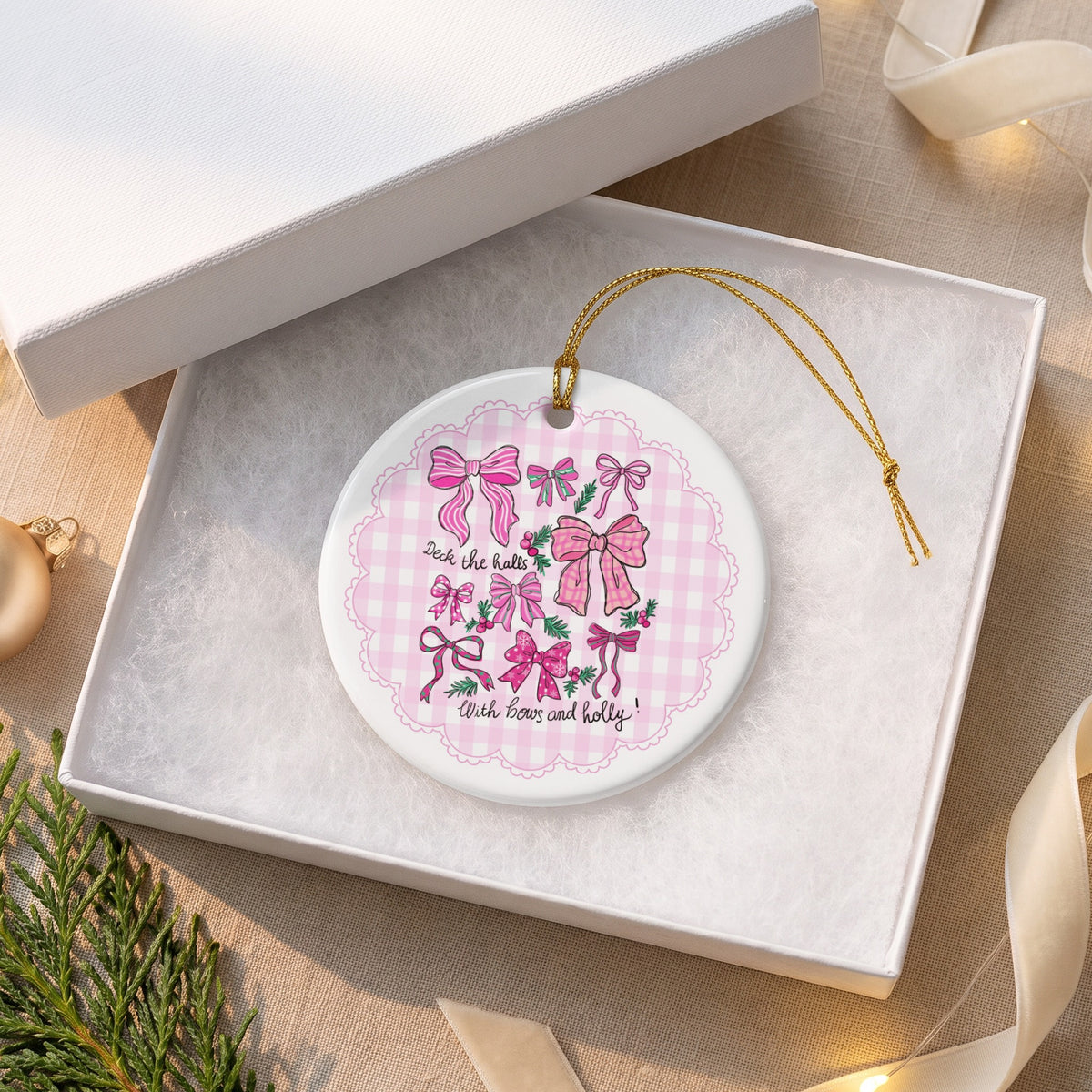 Round ornament with pink bows and holly, reads "Deck the halls with bows and holly!"