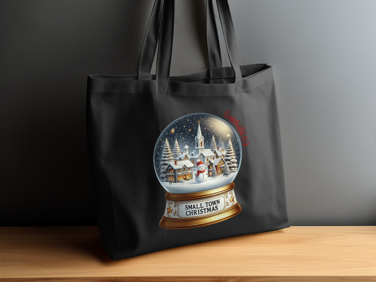 Black tote bag with a snow globe design featuring a snowman and small town.