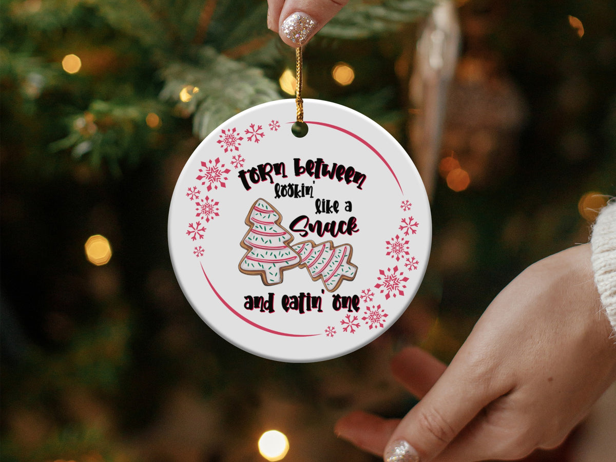 Round ornament with snowflakes, cookies, and text "Torn between lookin' like a snack and eatin' one."