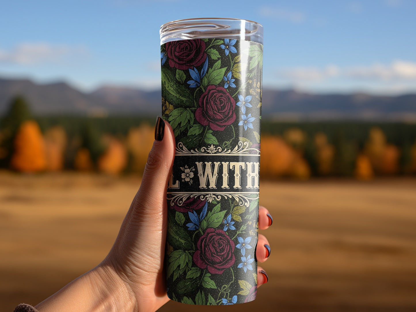 Tumbler with floral design and "WITH" text held by hand.