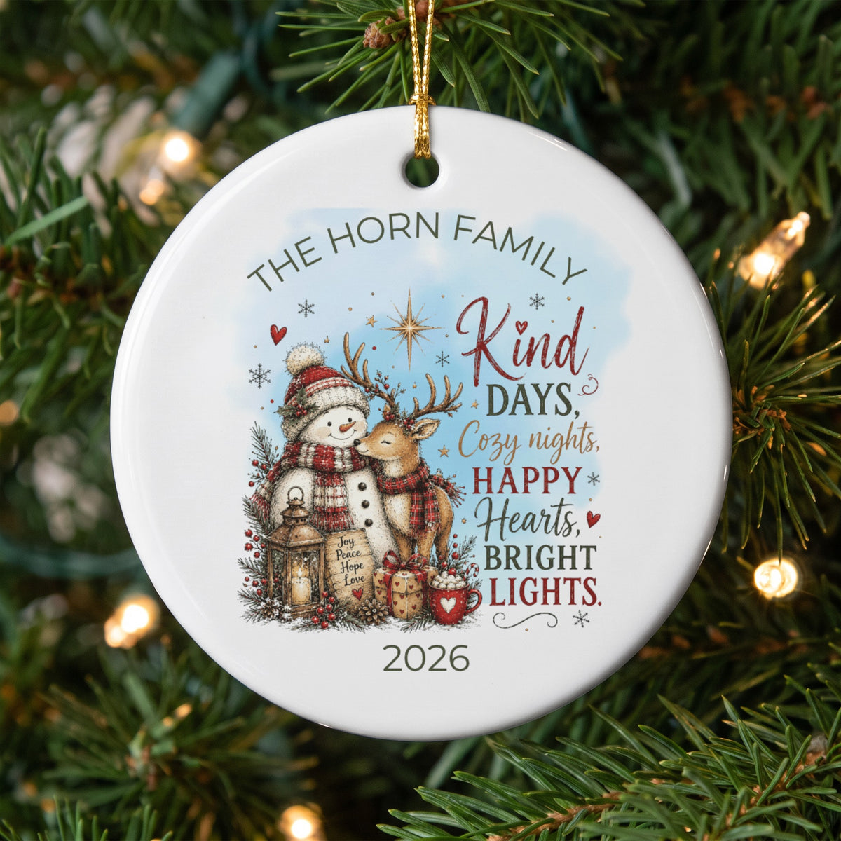 A round white Christmas ornament hanging on a tree features a snowman, a reindeer, the Horn Family name, and the year 2026.