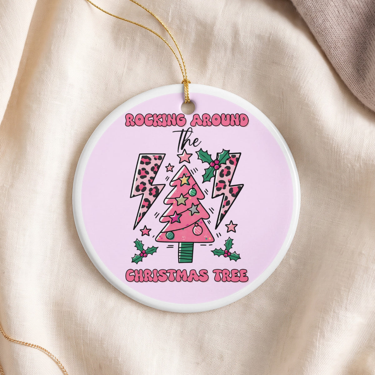 Round ceramic ornament with pink Christmas tree, leopard print lightning bolts, and text.