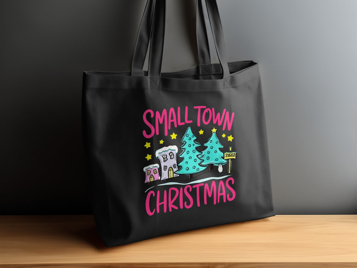 Black tote bag with "SMALL TOWN CHRISTMAS" design featuring trees, houses, and a zip code.