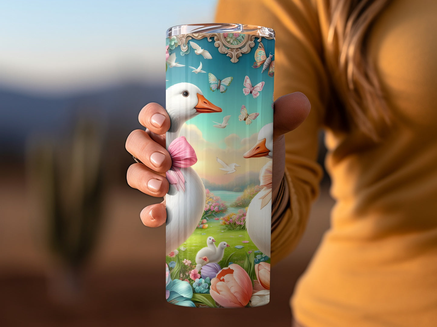 Goose with pink bow on tumbler, surrounded by butterflies and flowers.