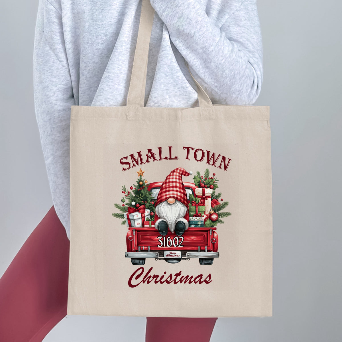 Tote bag with a gnome in a red truck filled with Christmas gifts and greenery.