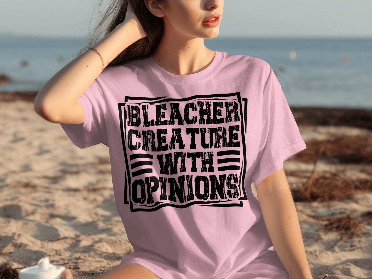 Pink t-shirt with "Bleacher Creature with Opinions" text on a woman on the beach.