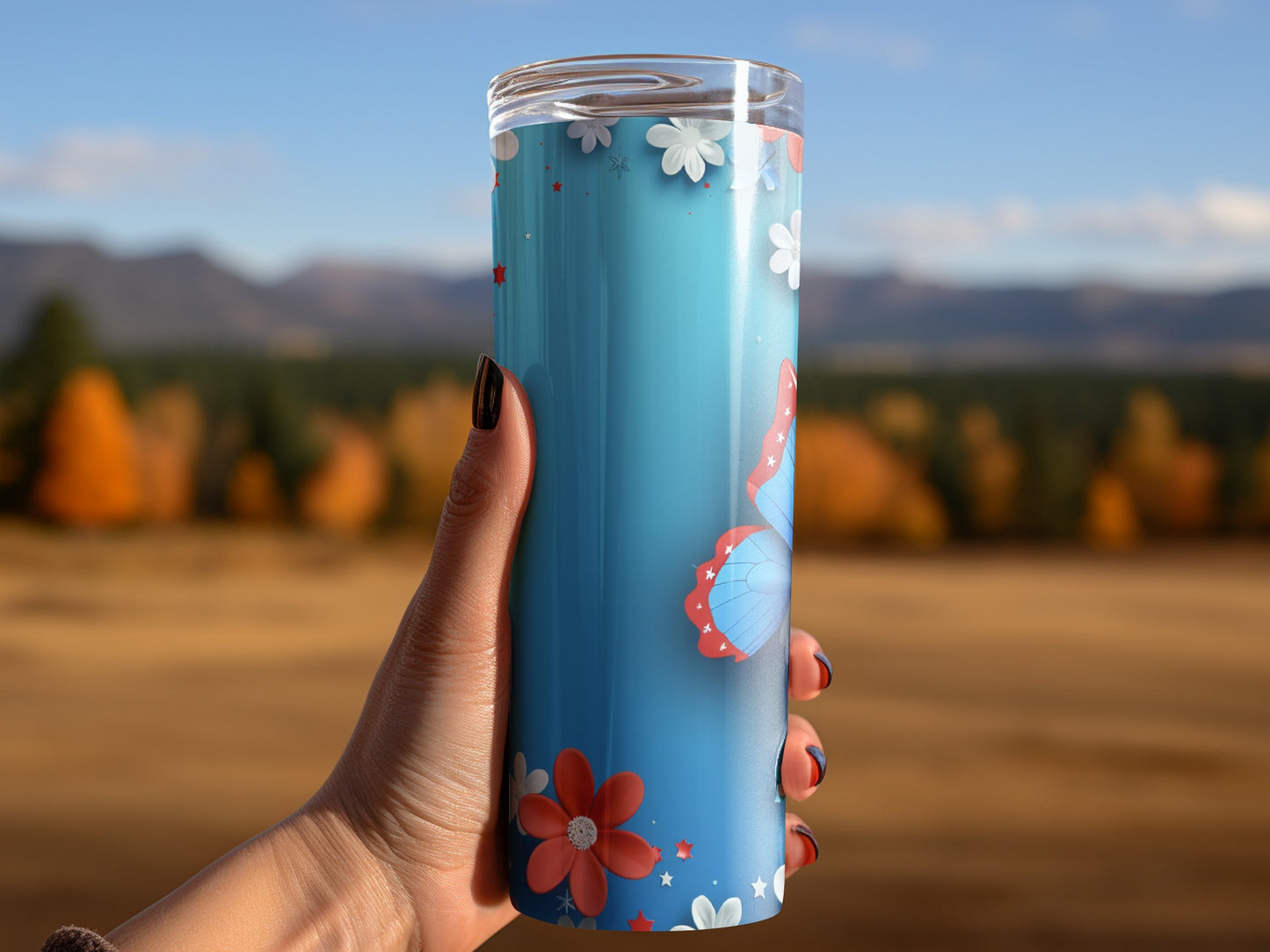 Blue tumbler with butterflies and flowers, held by a hand.