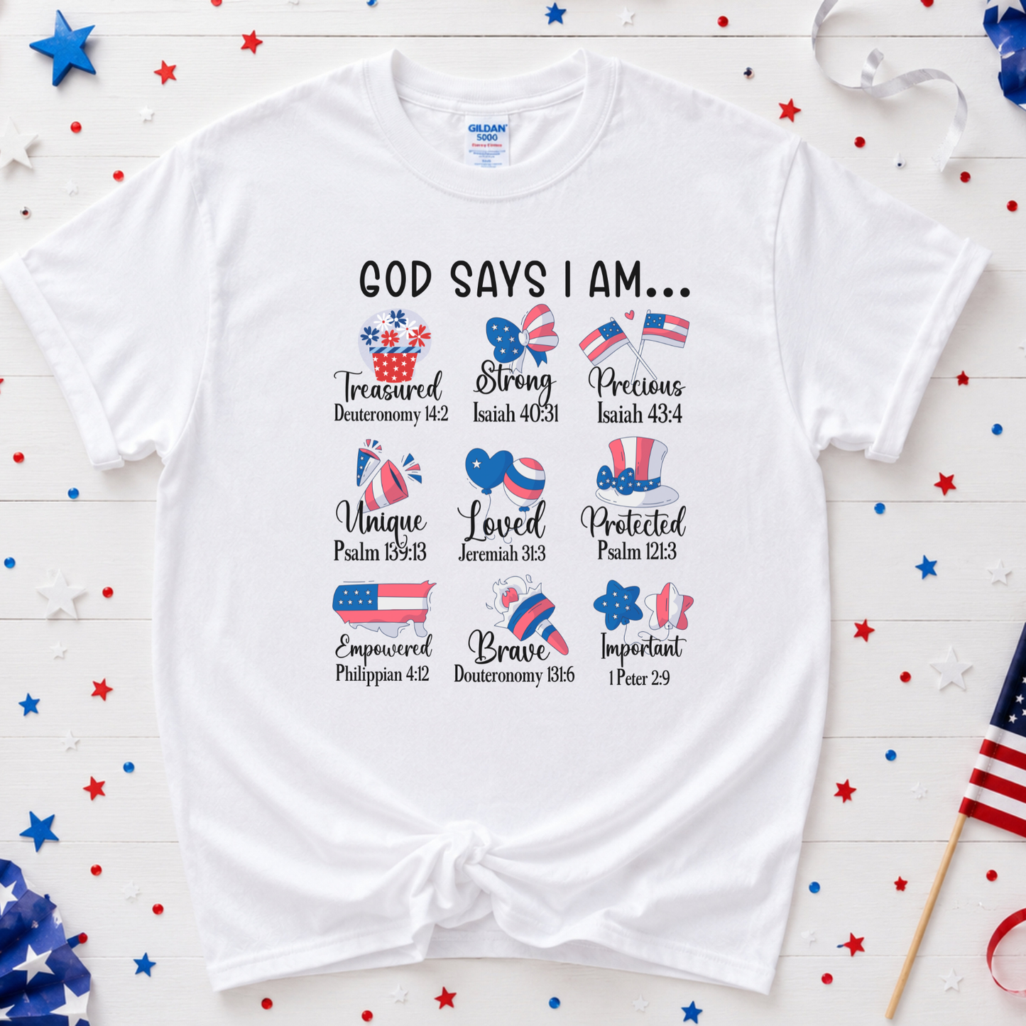 White t-shirt with Christian phrases and American flags on a wooden surface with decorative stars and an American flag.