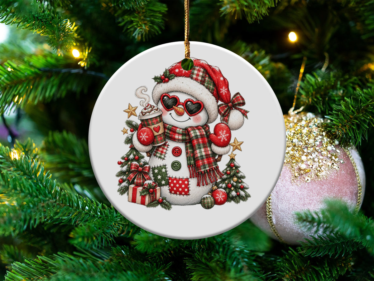 Christmas ornament featuring a snowman in a Santa hat, heart sunglasses, holding hot cocoa.
