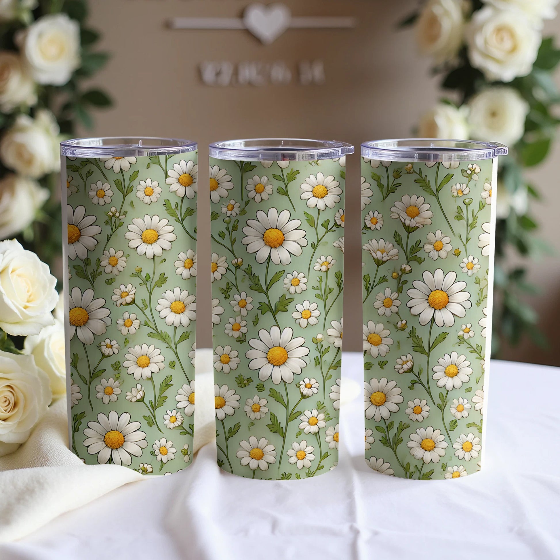 Three tumblers with a green daisy floral pattern arranged in a row.