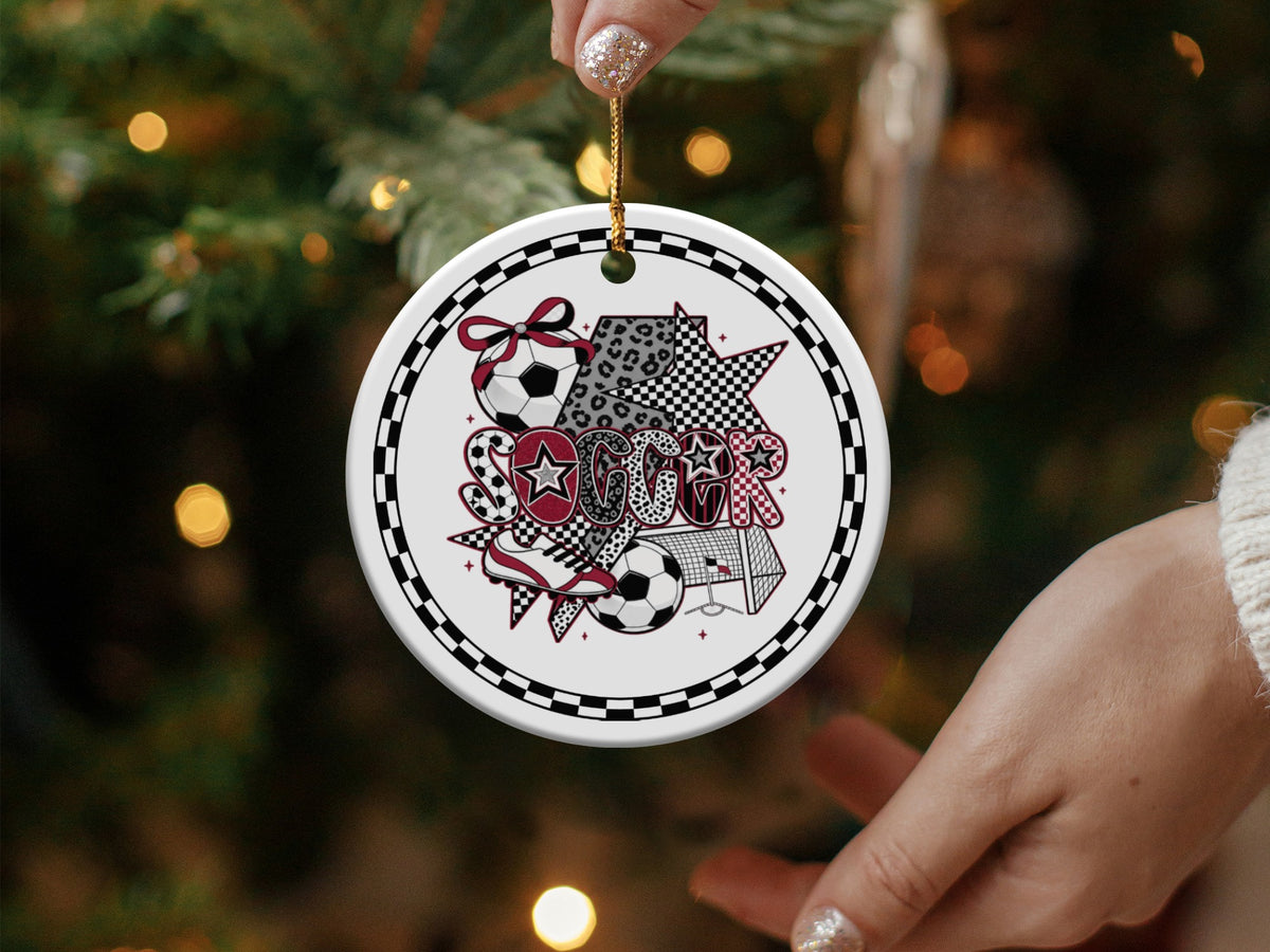 Round ceramic ornament with soccer ball, goal, and "Soccer" text on Christmas tree.