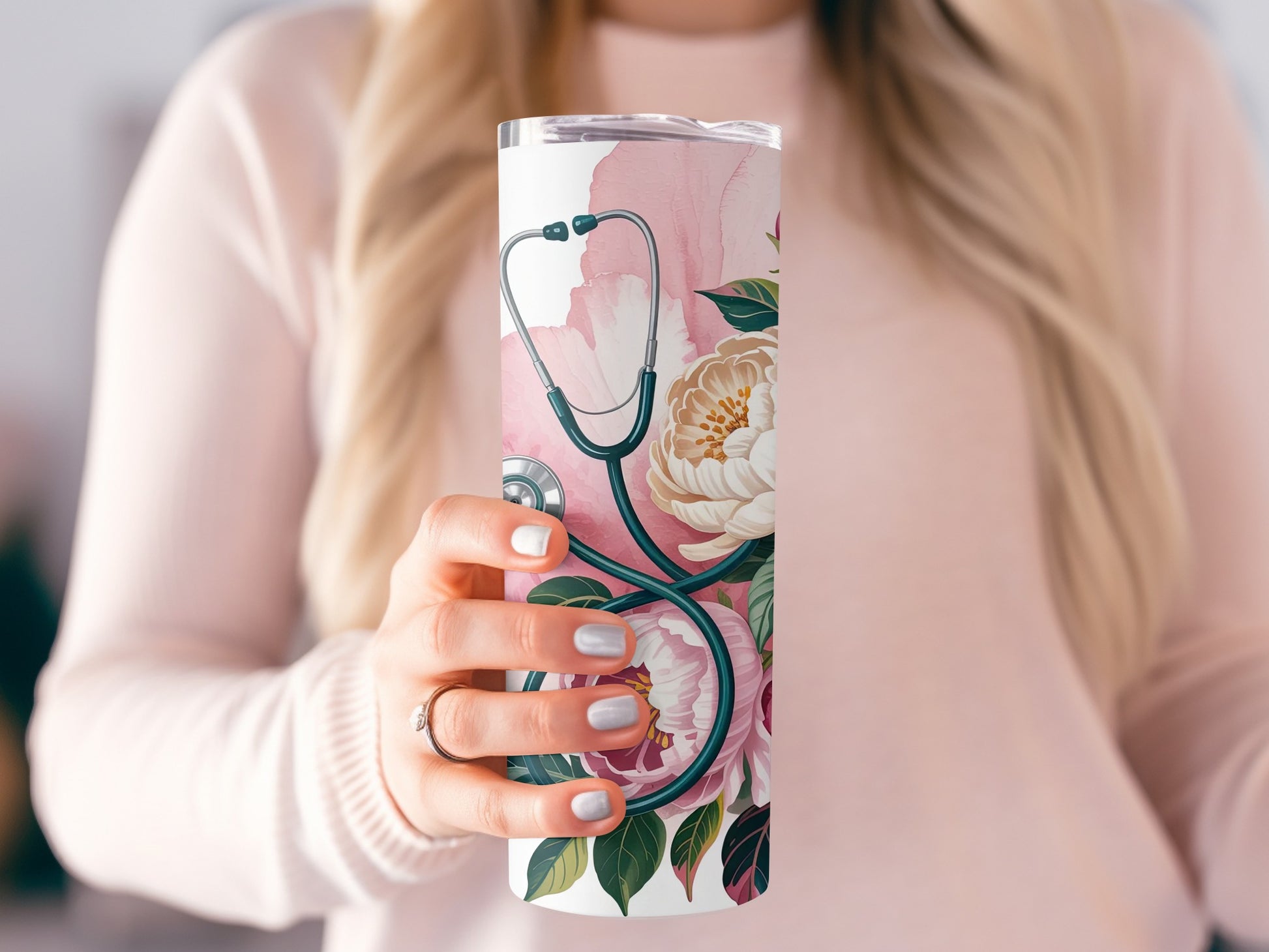 White tumbler with stethoscope and pink floral design held by a woman.