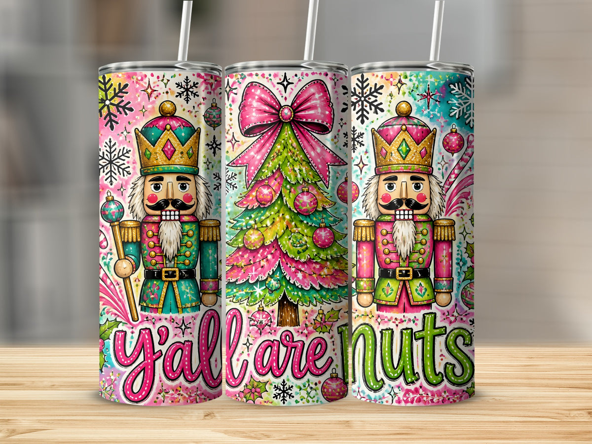 Three metal tumblers with straws feature a whimsical Christmas nutcracker and tree design with the text y'all are nuts.