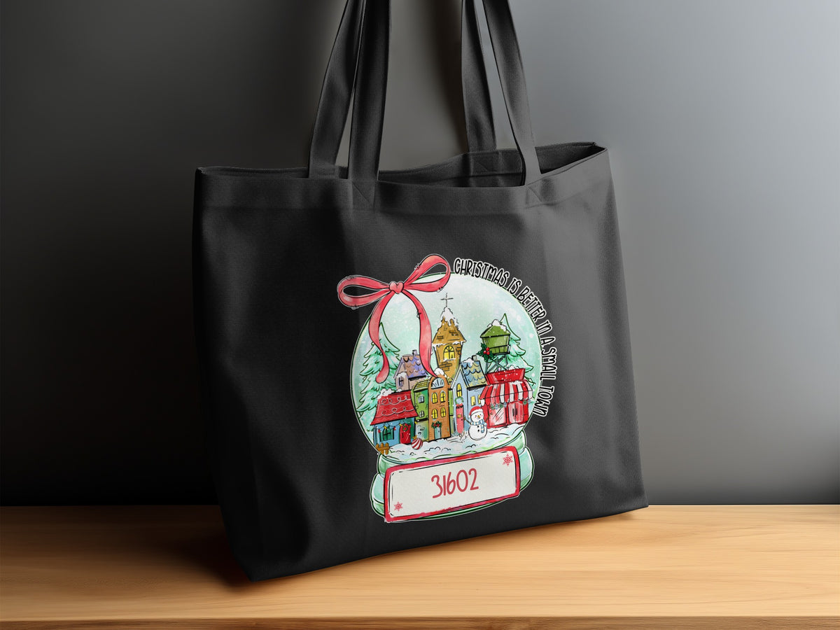 Black tote bag with a Christmas snow globe design featuring a small town and the number 31602.