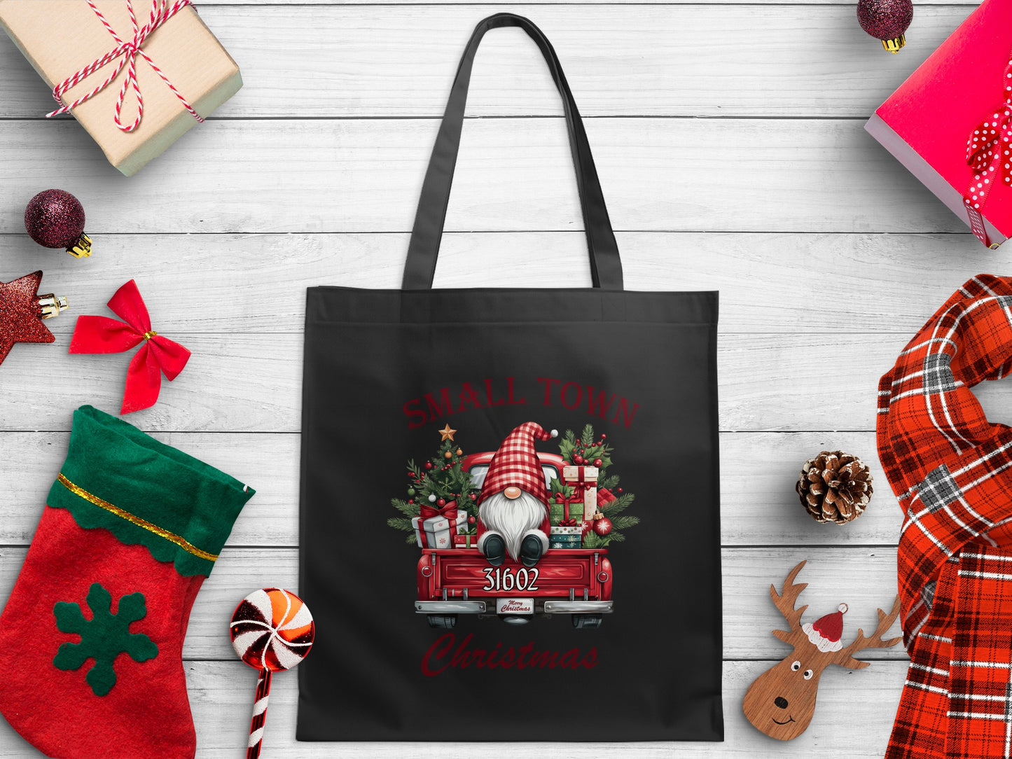 Black tote bag with Christmas gnome in red truck graphic and "Small Town Christmas" text.