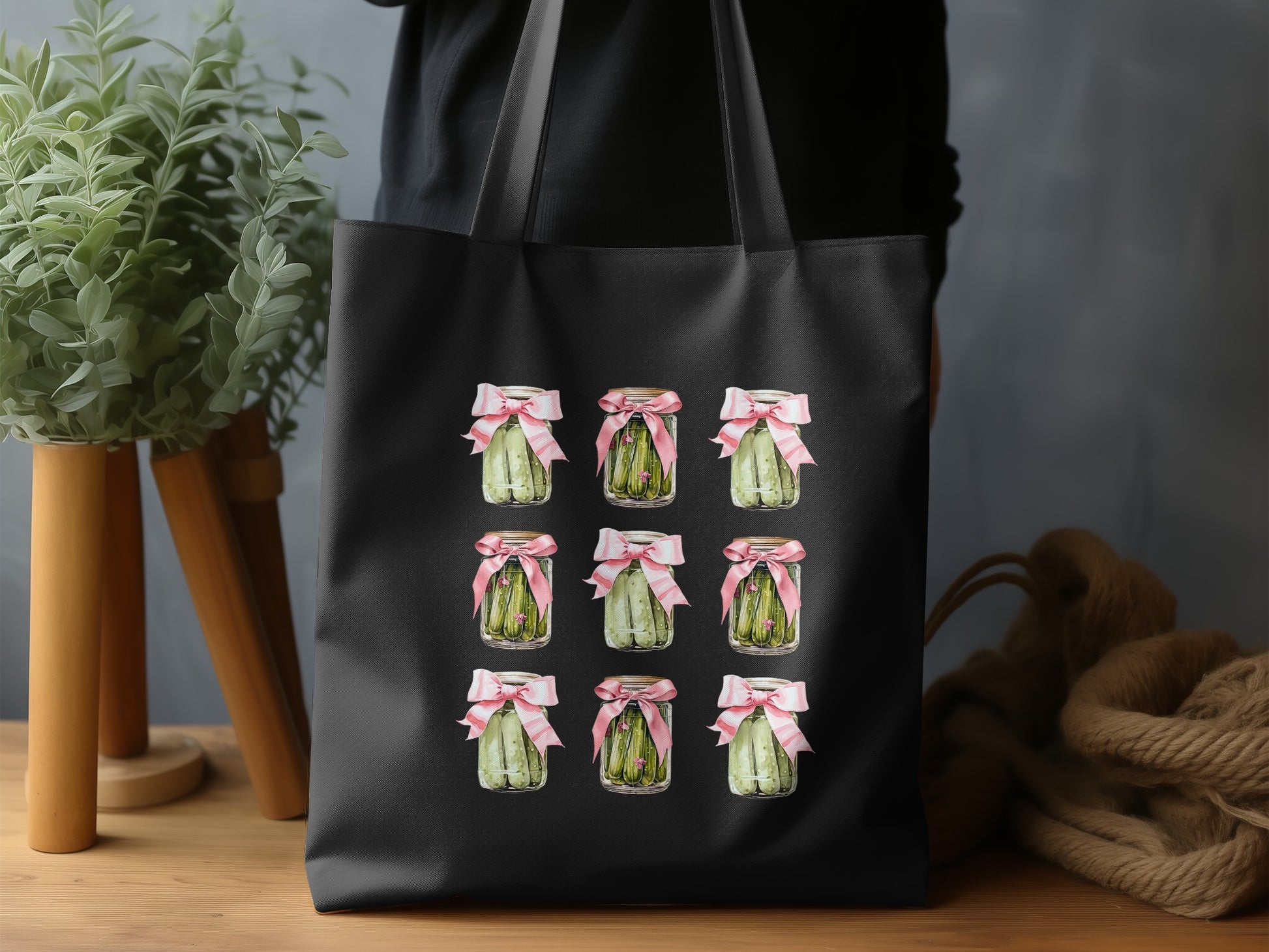 Black tote bag with nine jars of pickles tied with pink ribbon.