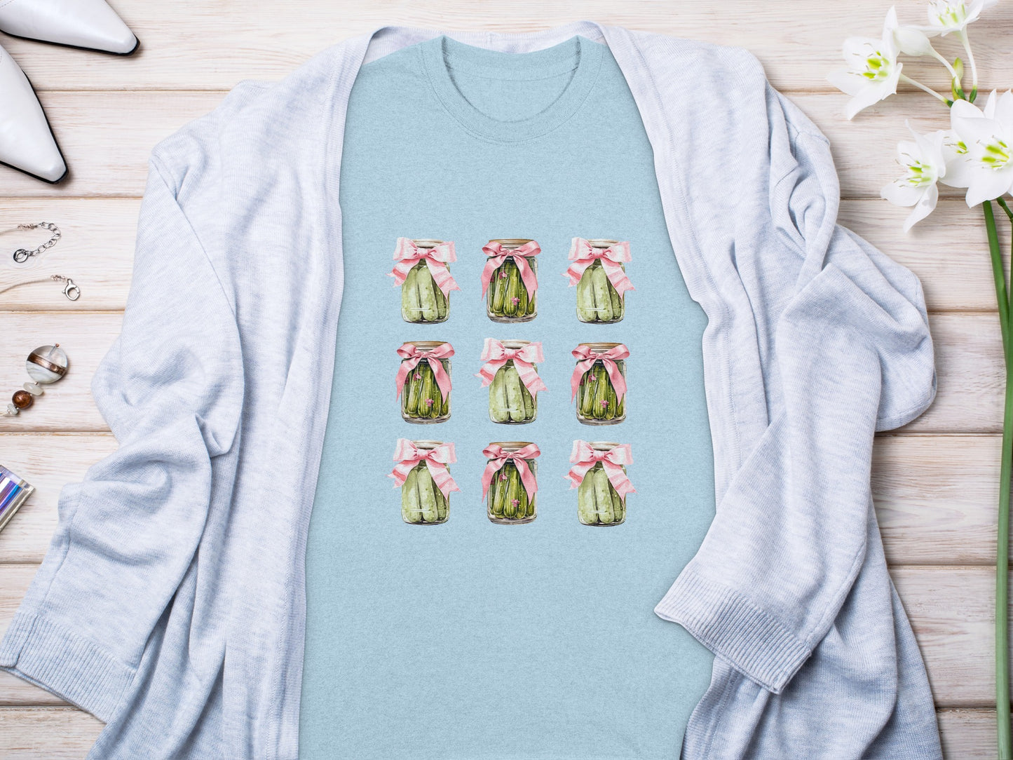 Light blue t-shirt featuring a watercolor grid of green beans in jars tied with pink bows.