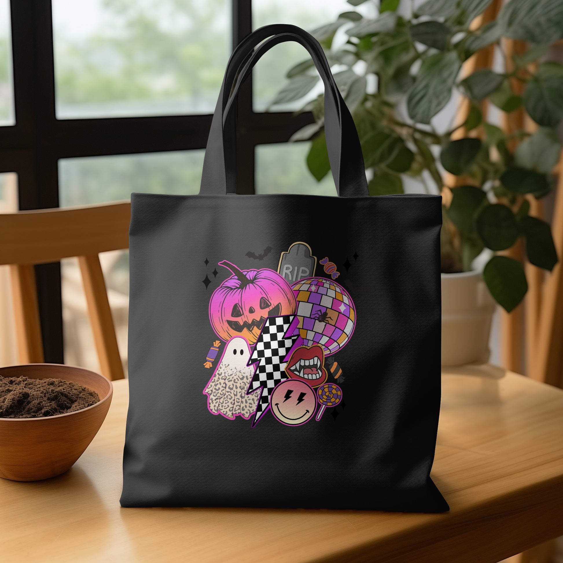 Black tote bag with Halloween graphic featuring pumpkin, ghost, disco ball, and smiley face.