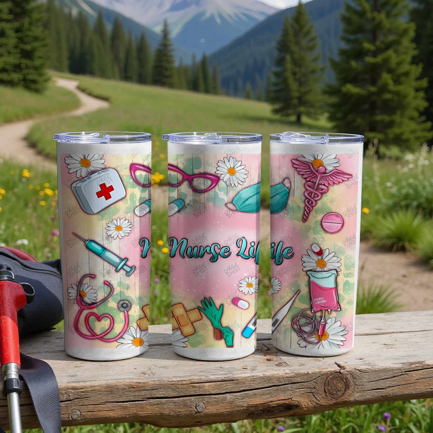 Three tumblers with nurse-themed designs on a wooden surface, mountains in background.