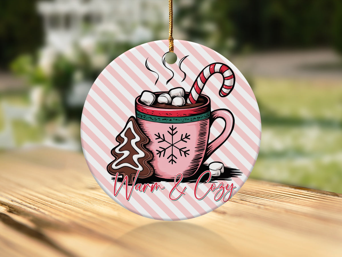 Round ornament with hot chocolate, candy cane, gingerbread tree, and "Warm & Cozy" text.