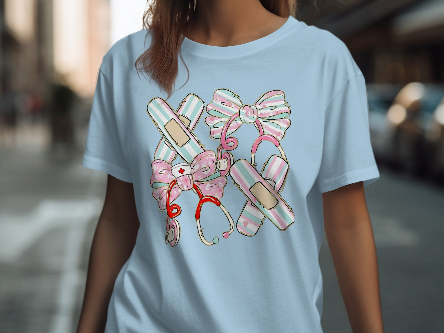 Light blue t-shirt with medical-themed graphic: stethoscope, bandages, and bows.