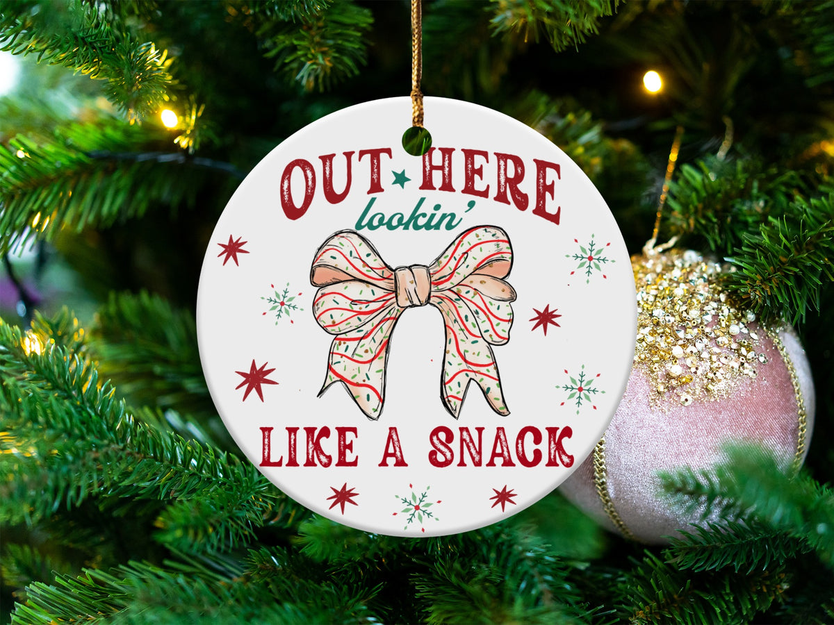 Round ornament with red text "OUT HERE lookin' LIKE A SNACK" and a bow.
