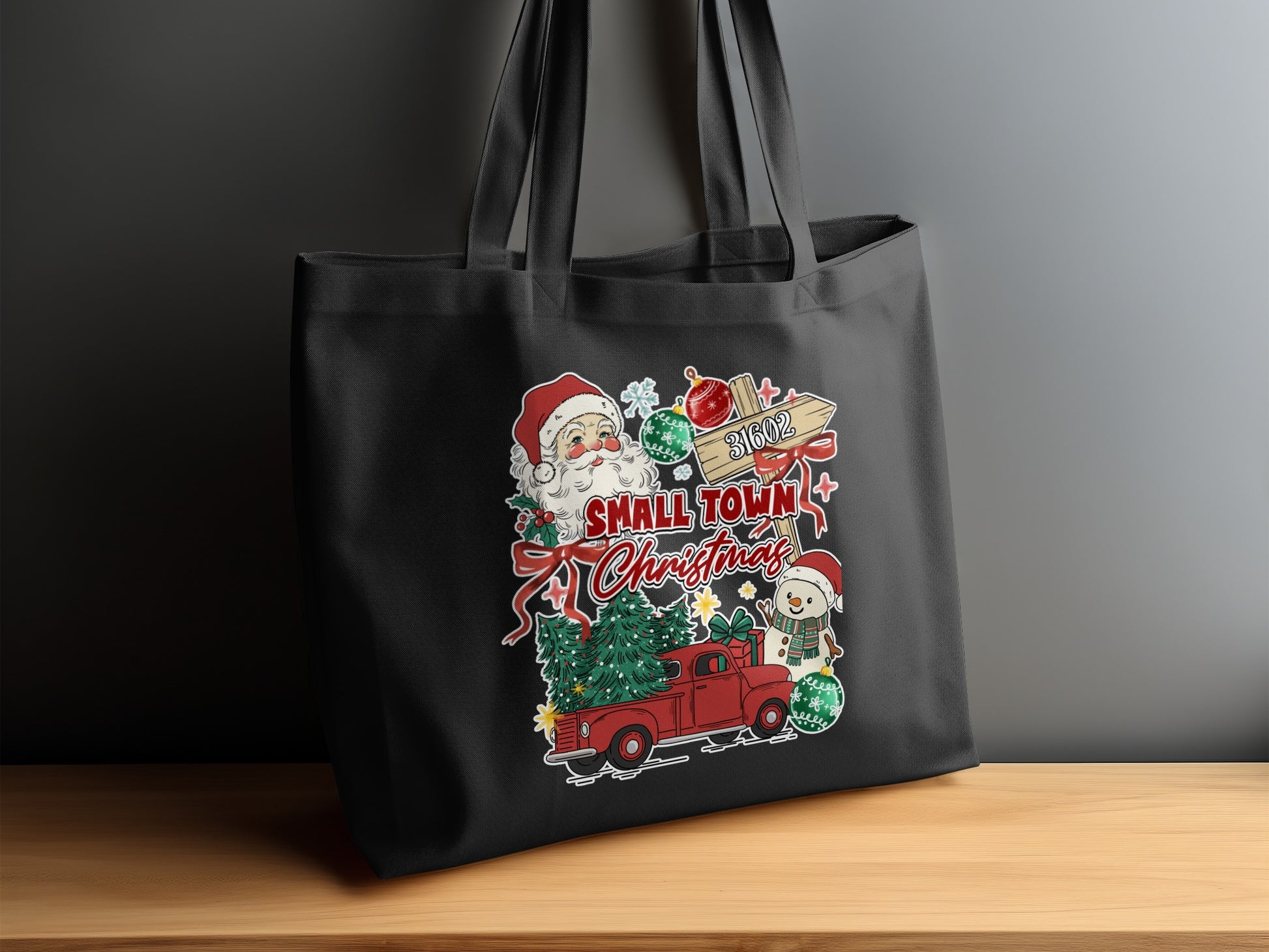 Black tote bag with "Small Town Christmas" design featuring Santa, snowman, truck, and trees.