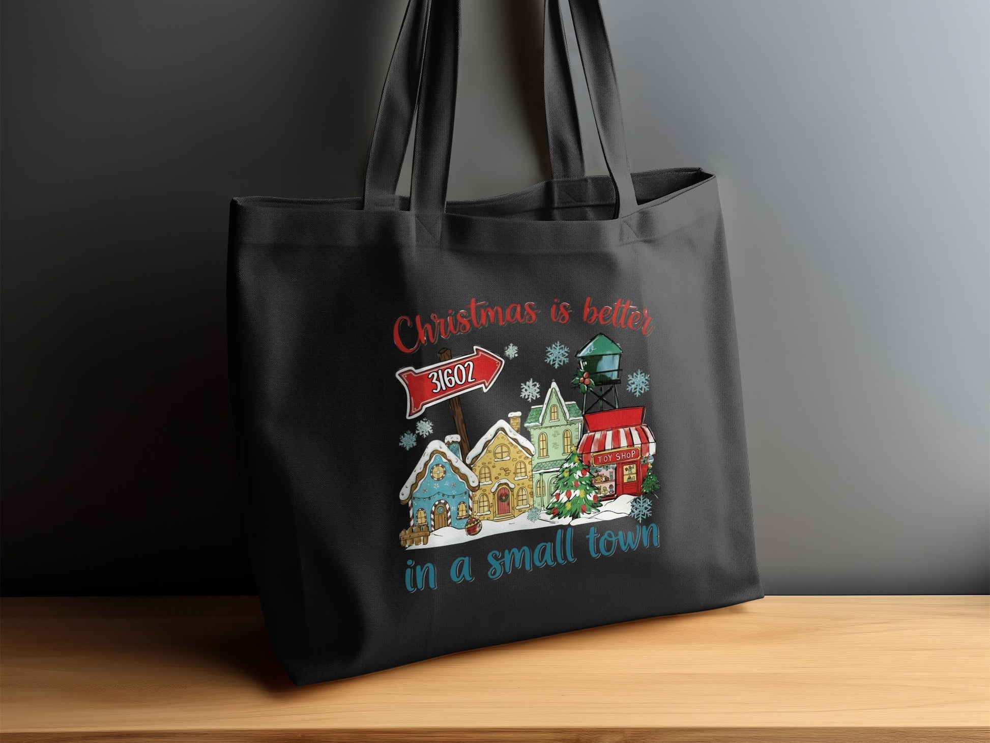 Black tote bag with Christmas village graphic and text, "Christmas is better in a small town."
