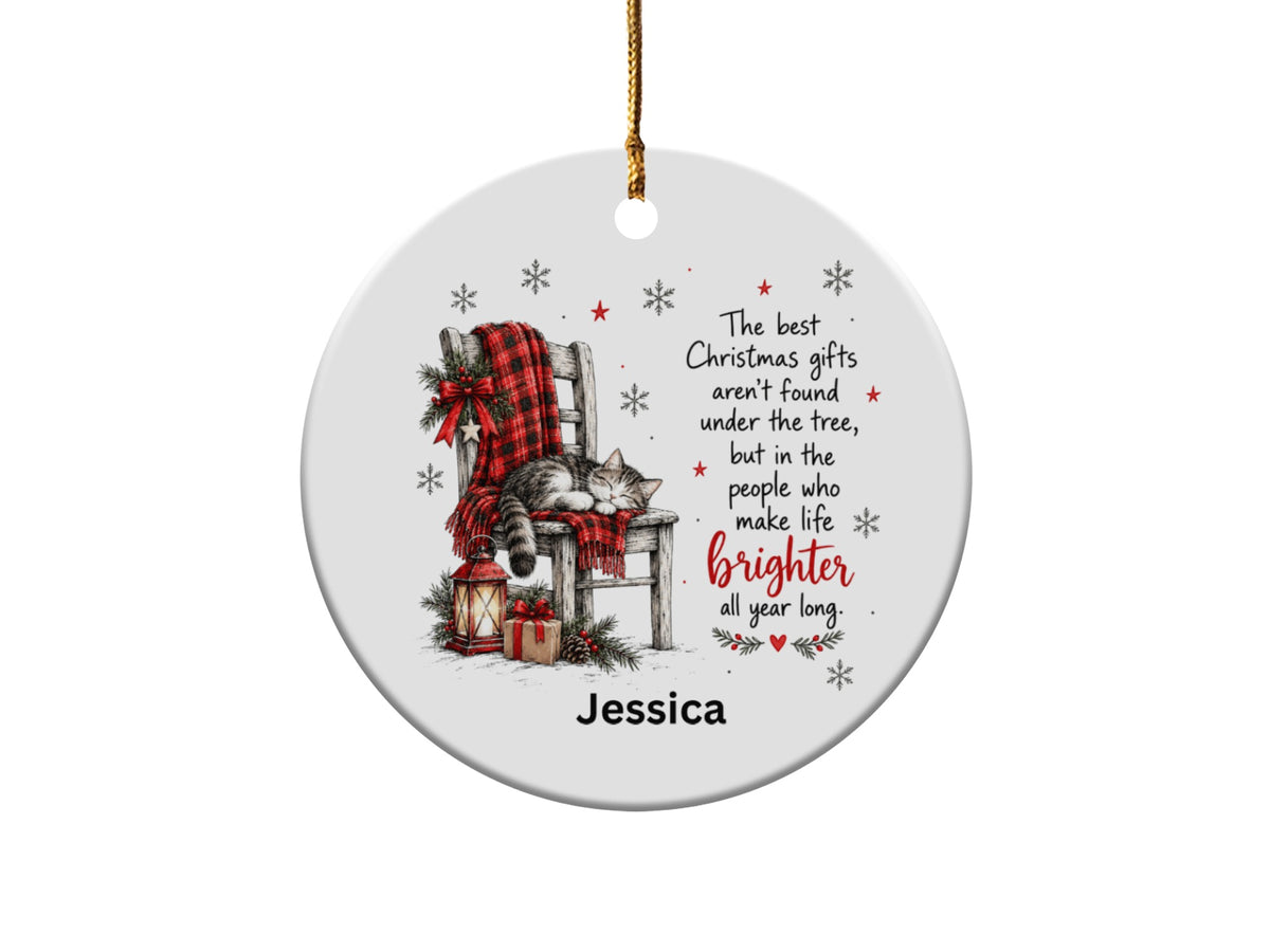 A round white ceramic Christmas ornament featuring a sleeping cat on a chair, holiday text, and the name Jessica.