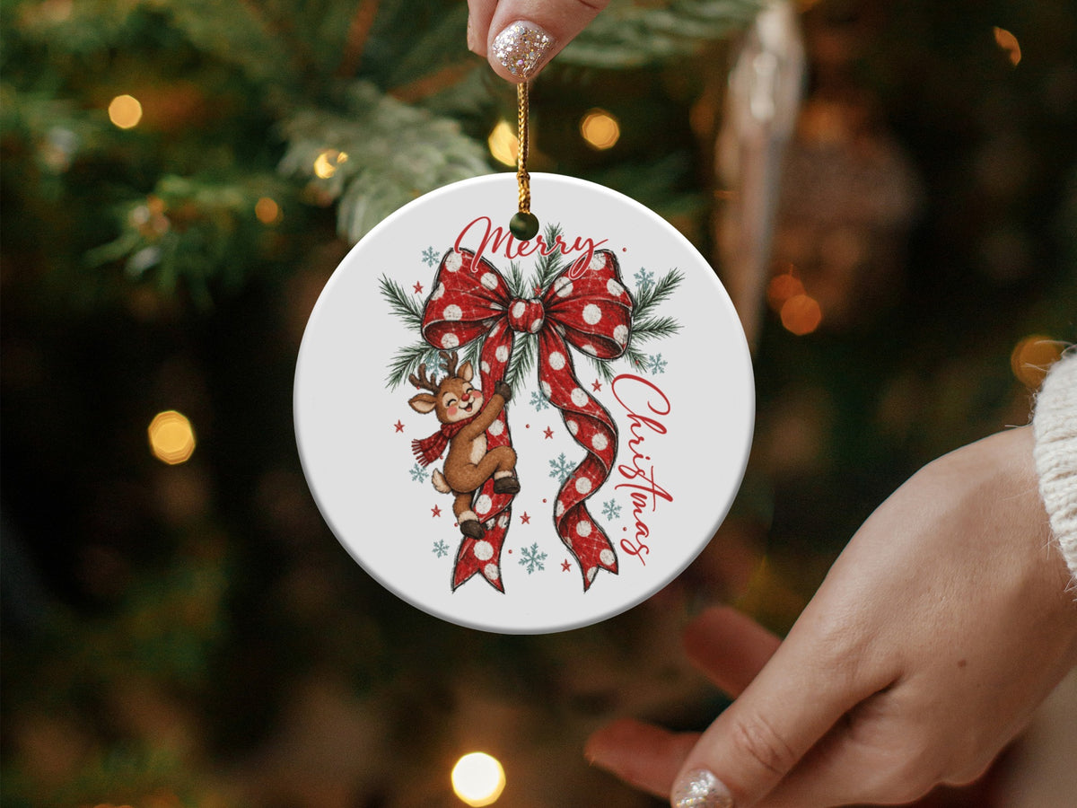 Round Christmas ornament with a reindeer, red polka dot bow, and pine sprigs.