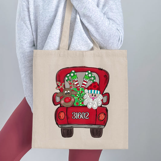 Tote bag with red truck graphic featuring Santa, reindeer, gifts, and the number 31602.