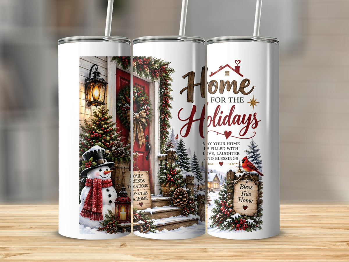Three tall, white tumblers with straws stand on a wooden surface, displaying a wrap-around Christmas scene with a snowman, decorated porch, and holiday text.