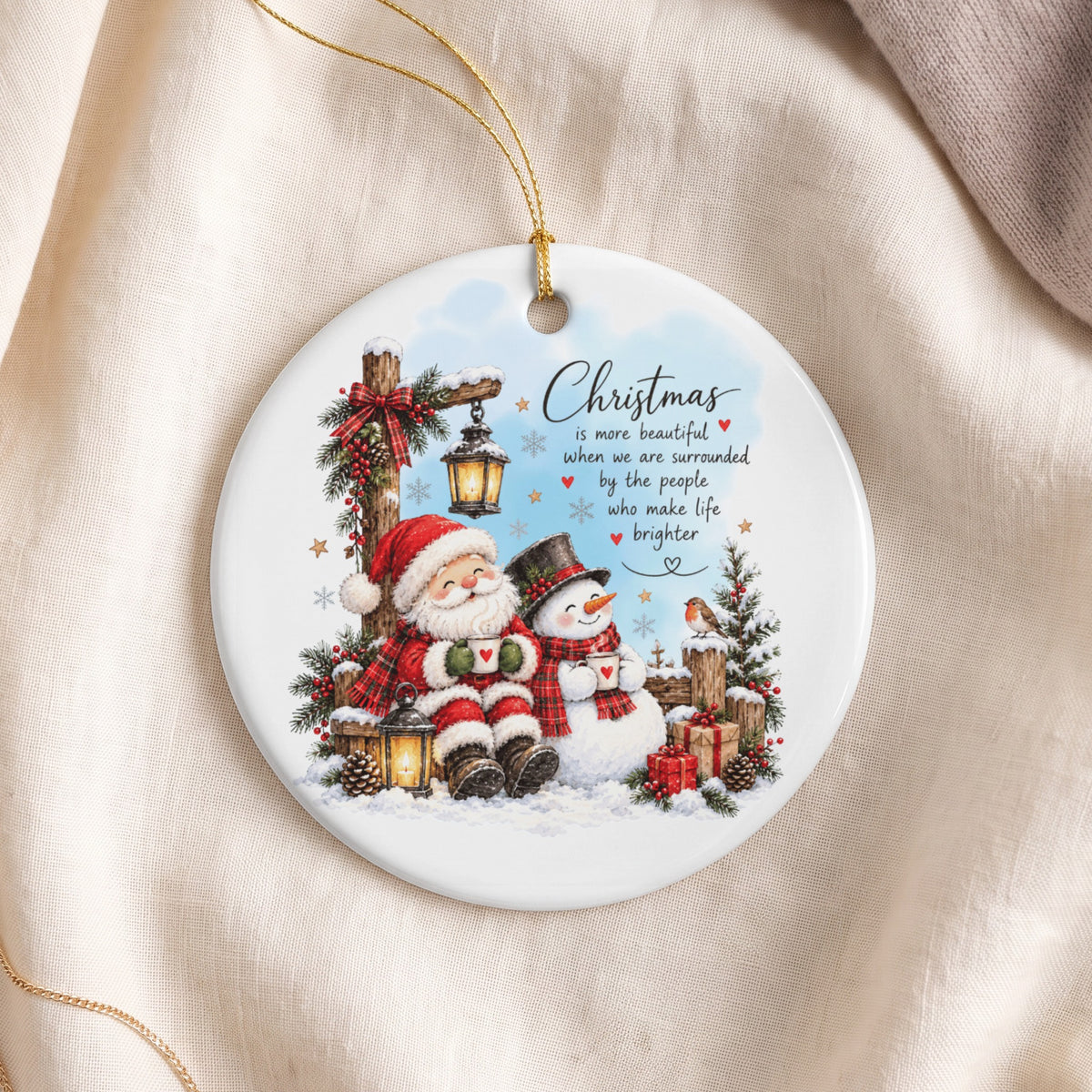 Round ceramic Christmas ornament depicting Santa and a snowman drinking from mugs, with inspirational holiday text.