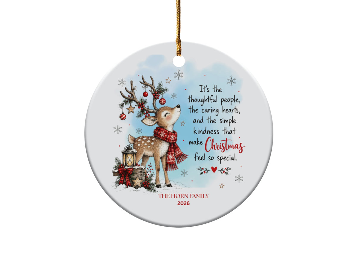 Round white ceramic Christmas ornament featuring a fawn wearing a red scarf, holiday text, and family name.