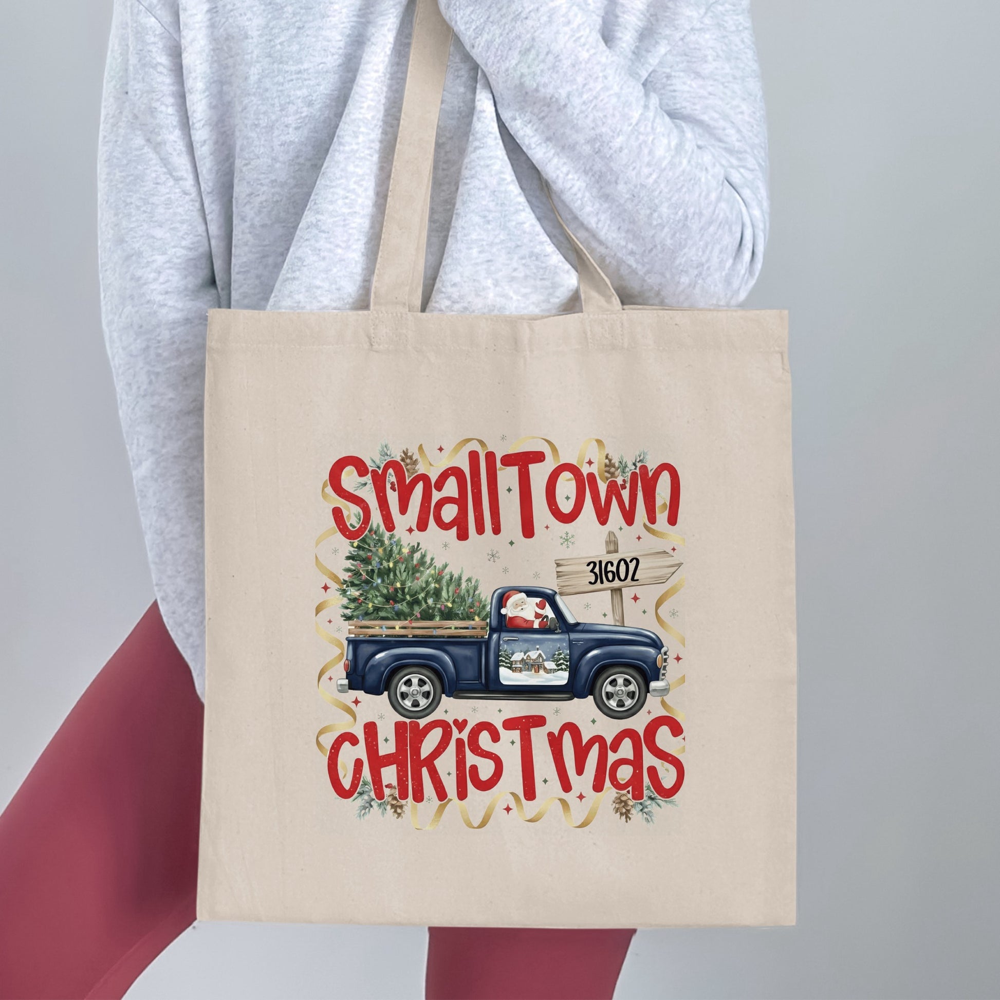 Tote bag with "Small Town Christmas" text, blue truck, and Santa.