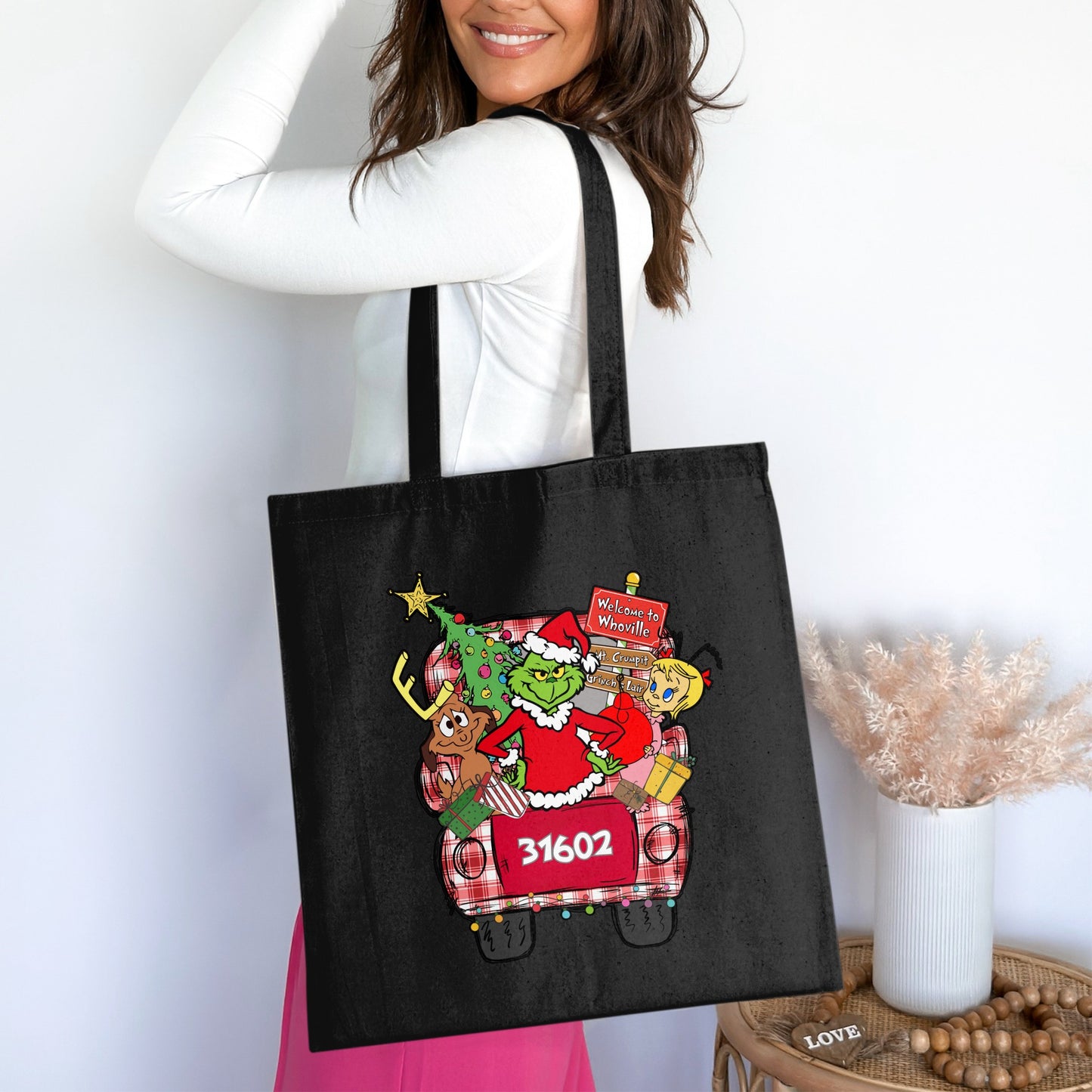 Black tote bag with a Grinch-themed Christmas truck graphic and zip code 31602.