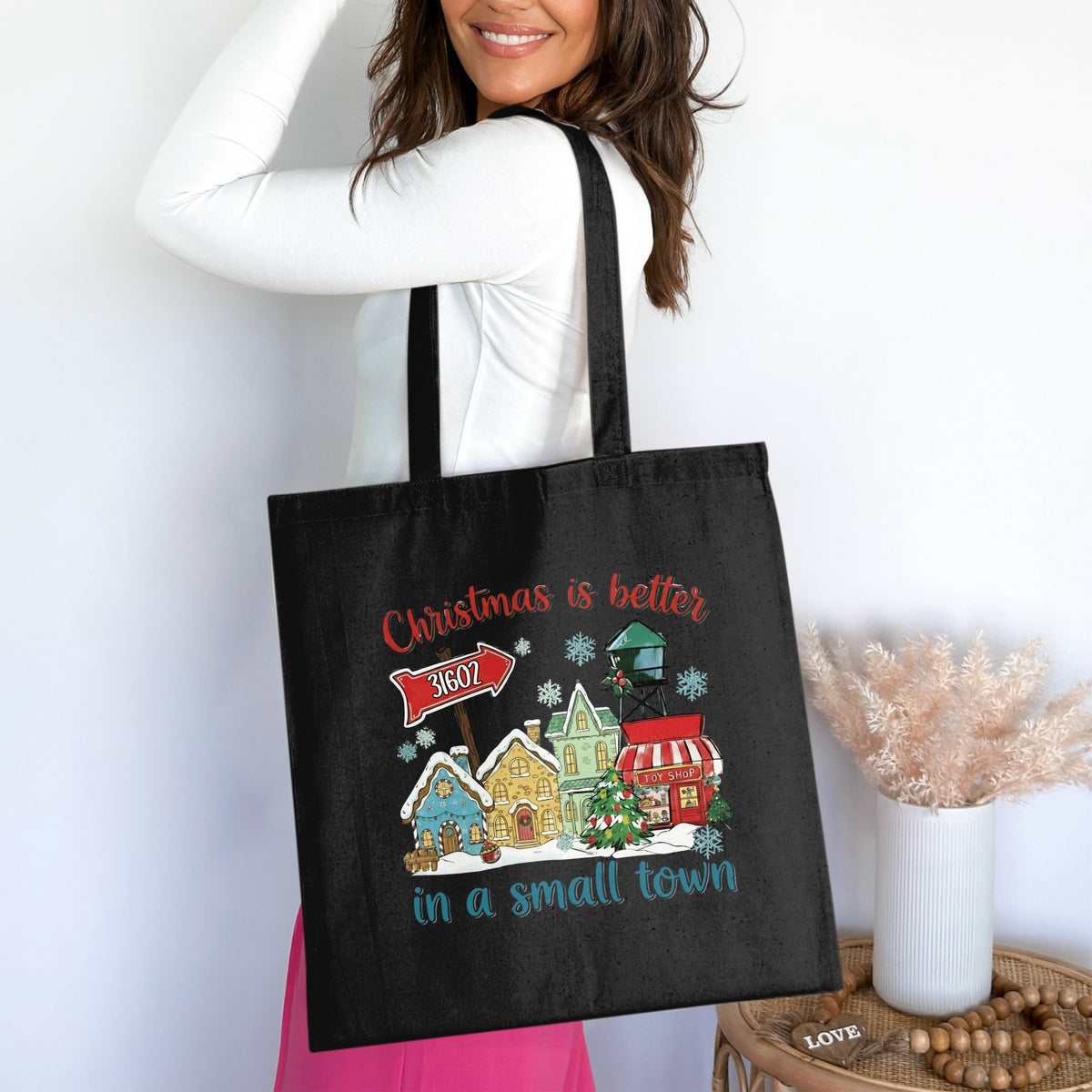 Black tote bag with a Christmas village design and text "Christmas is better in a small town."