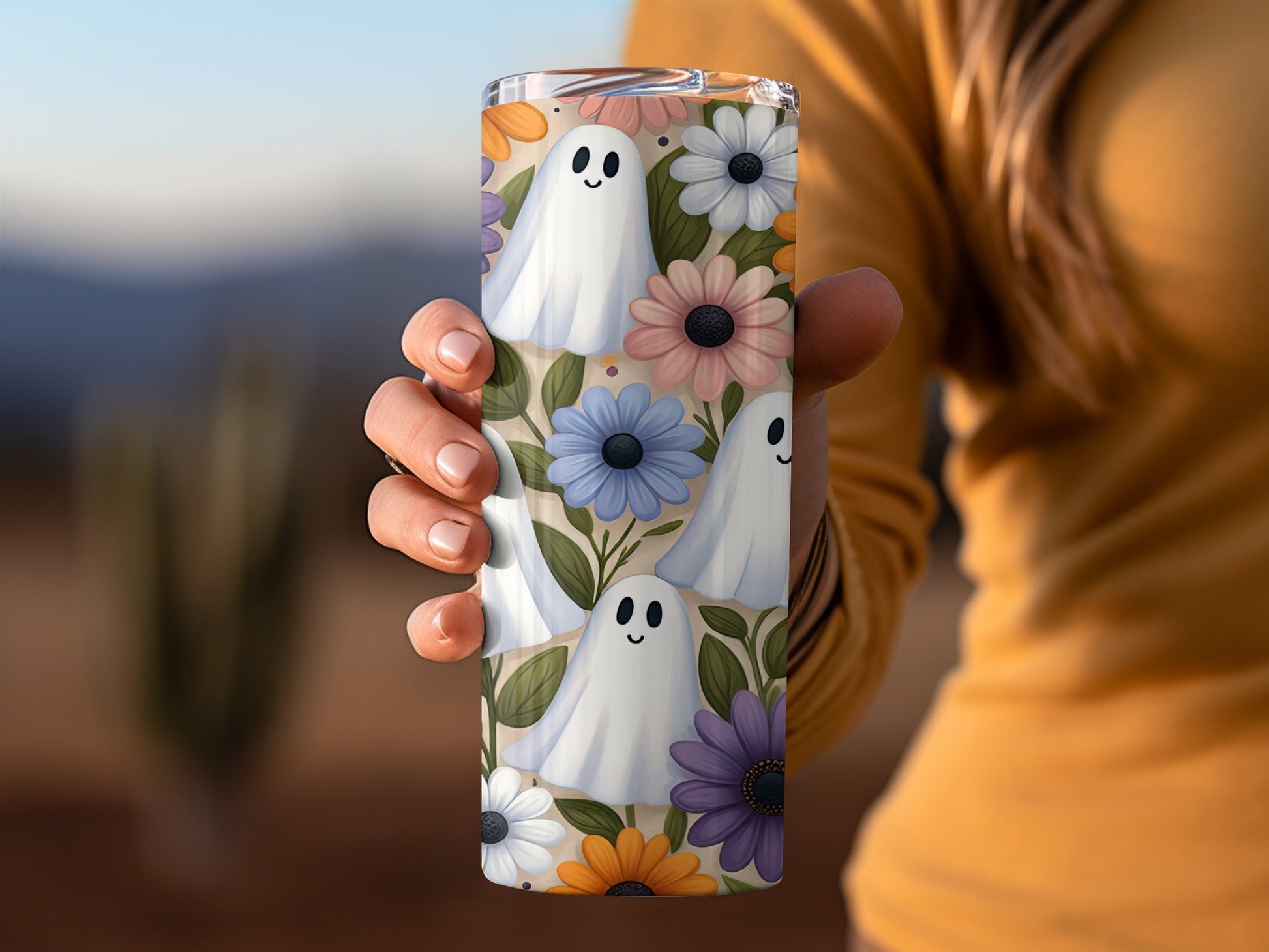 Tumbler with ghosts and pastel flowers pattern held by a person.