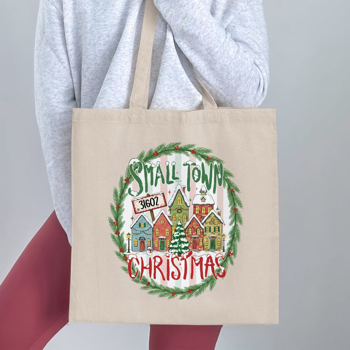 Canvas tote bag with "Small Town Christmas" design featuring snow-covered houses and festive wreath.