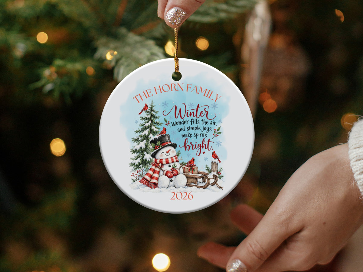 A round white ceramic Christmas ornament featuring a snowman, winter illustrations, and the text The Horn Family 2026.