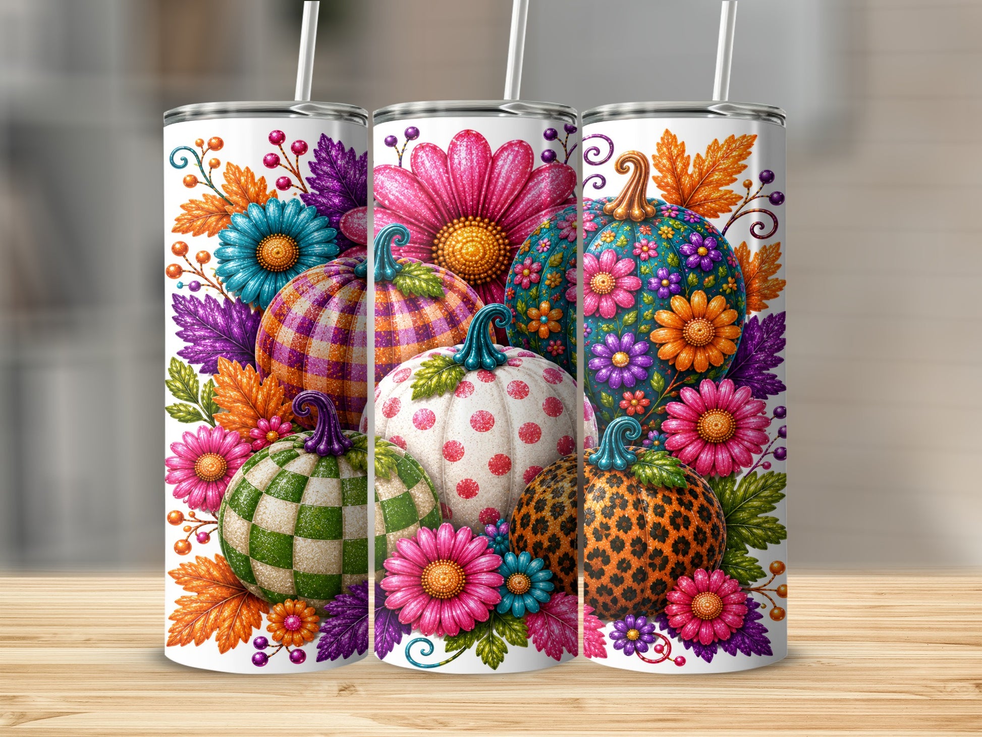 Three tumblers decorated with colorful pumpkins, flowers, and autumn leaves at a slight angle.