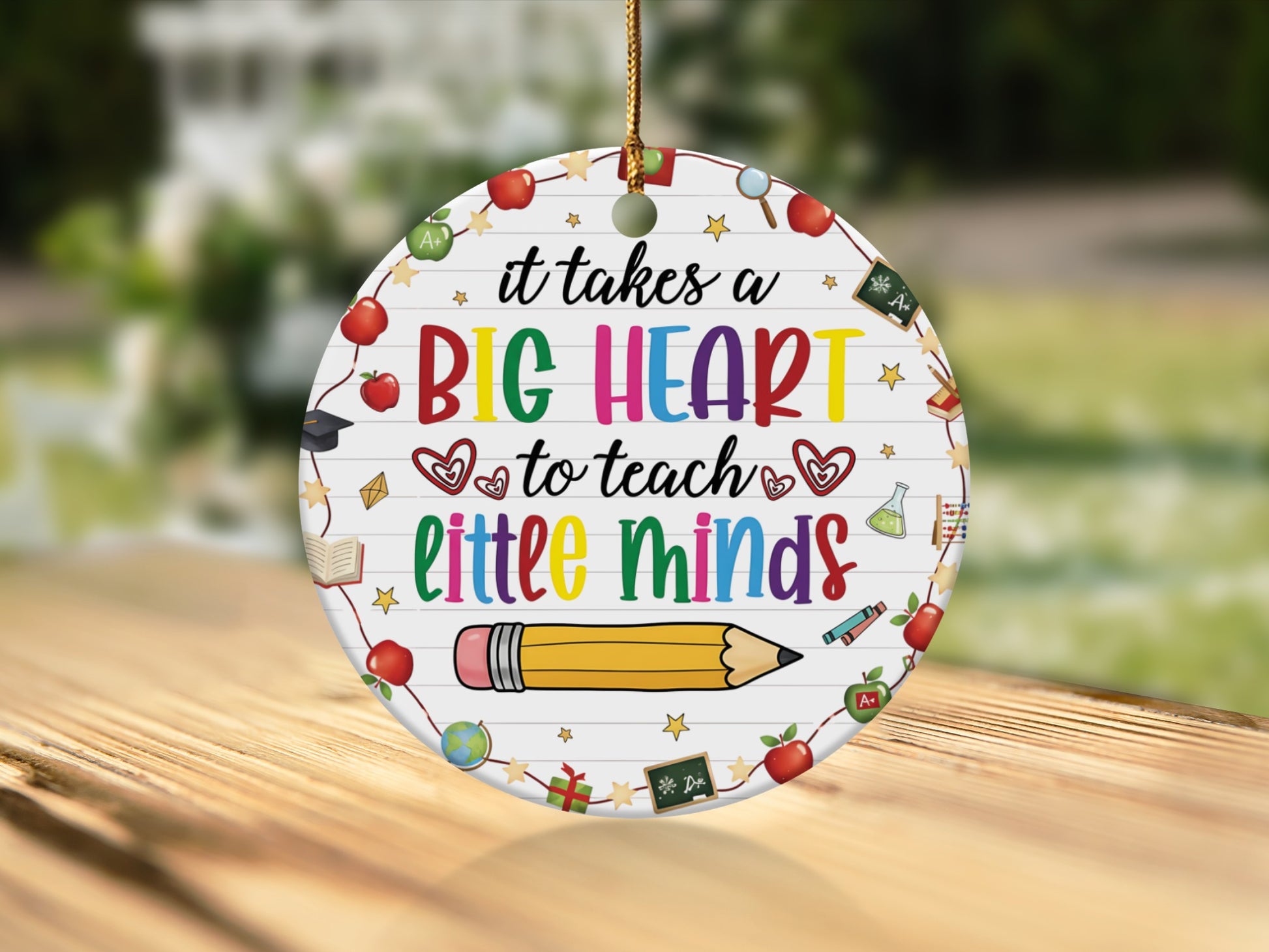 Round ornament with text "it takes a BIG HEART to teach little minds" and school icons.