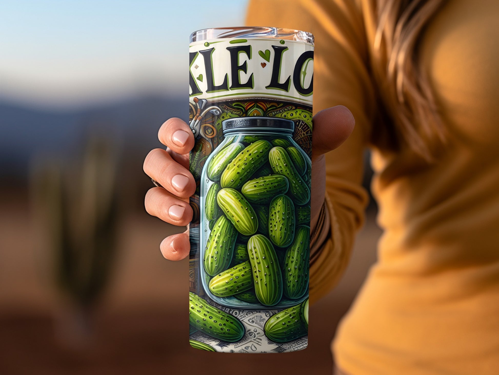 Jar of pickles with "Pickle Lo" text on a tumbler held by a hand.
