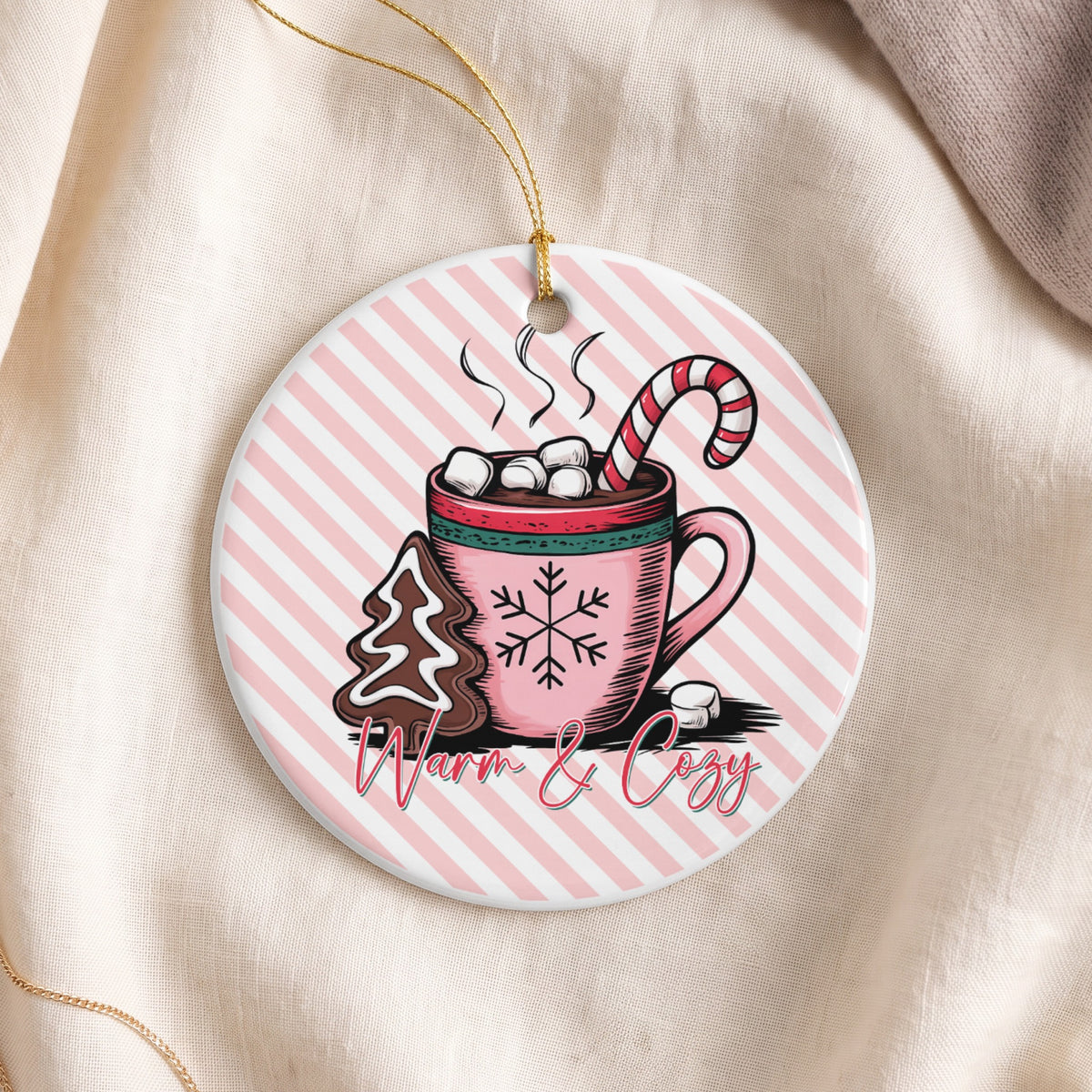 Round ornament with hot chocolate, candy cane, gingerbread cookie, and text "Warm & Cozy."